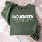 Green sweatshirt with the text undiagnosed but something ain’t right.