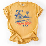 Yellow graphic t-shirt featuring In My Farm Wife Era text with a farmhouse and windmill design.