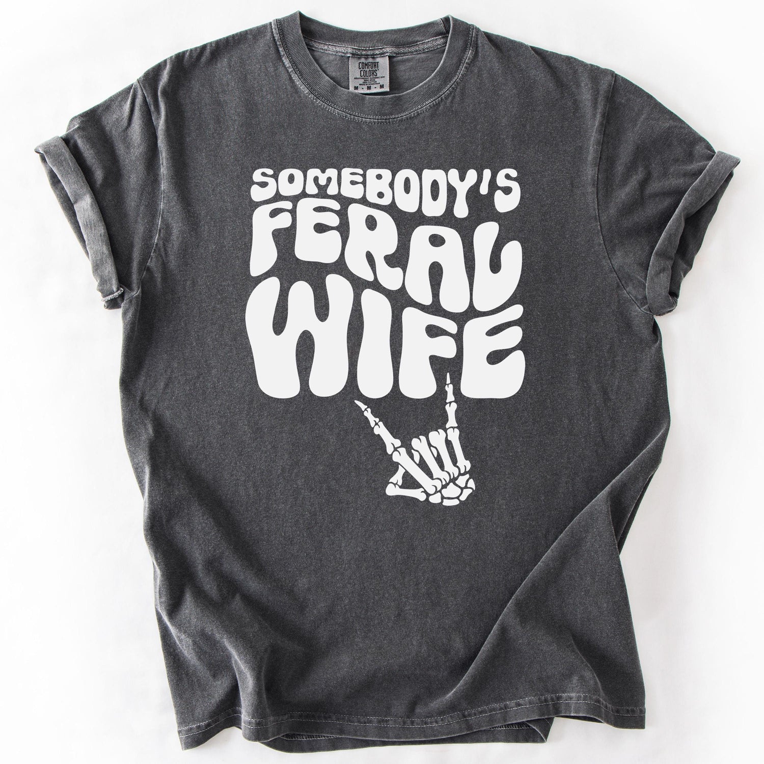 Charcoal gray graphic t-shirt with SOMEBODY'S FERAL WIFE text and skeleton hand design.