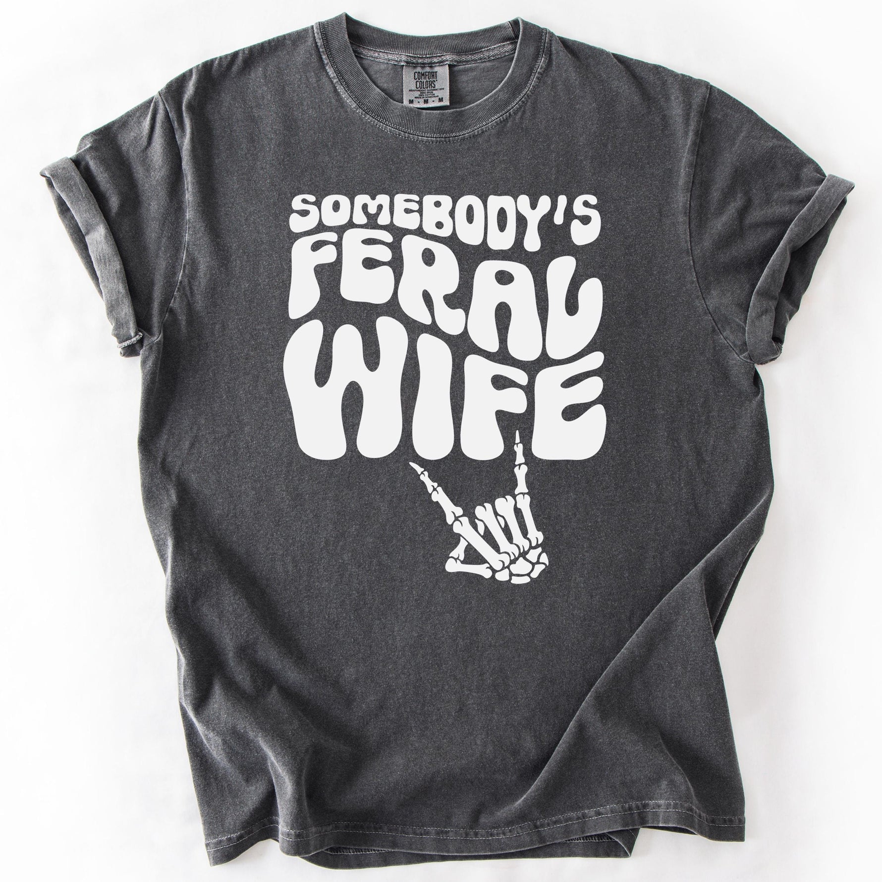 Charcoal gray graphic t-shirt with SOMEBODY'S FERAL WIFE text and skeleton hand design.
