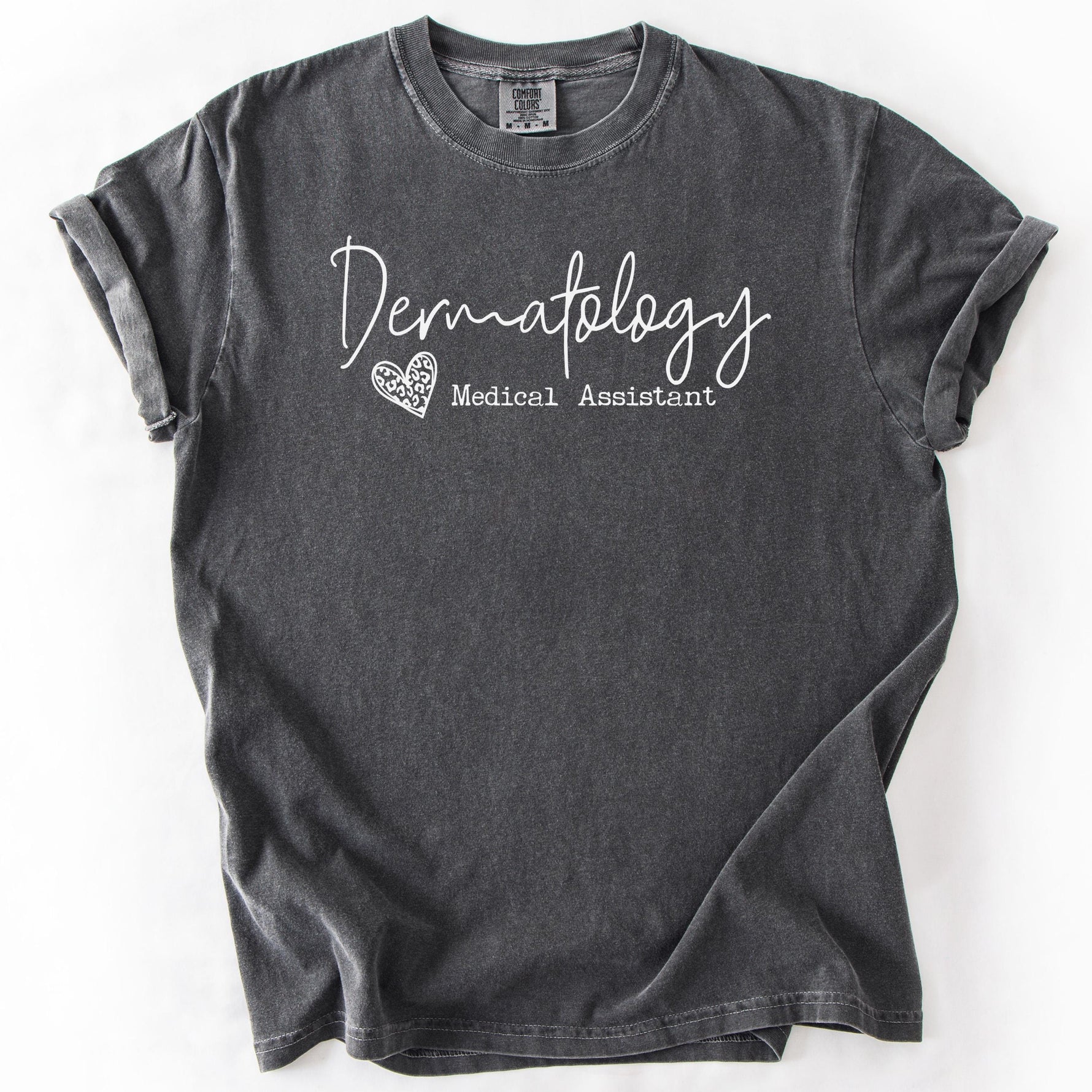 Charcoal gray, short-sleeve t-shirt with Dermatology Medical Assistant graphic.