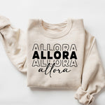 Beige sweatshirt with ALLORA text in various fonts. Personalize Print